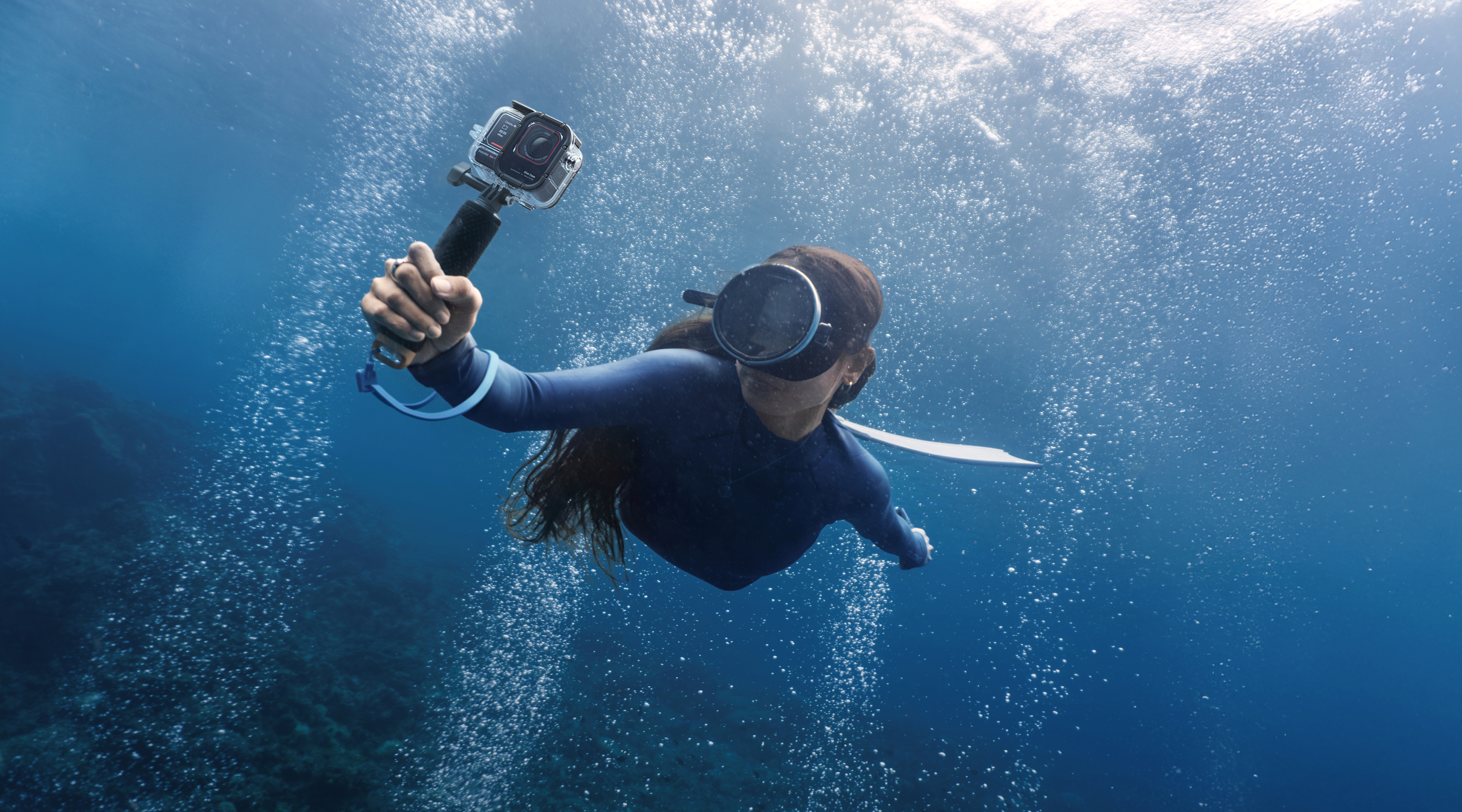 A free diver holding Insta360 Ace Pro 2 underwater with the Dive Case.